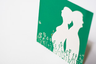 een groen geboortekaartje met de 2 silhouetten van toekomstige ouders in een voorgrond van gestileerde heide
