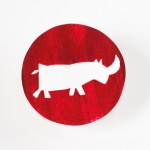 een cirkelvormig doopsuiker label met een neushoorn op een rode achtergrond